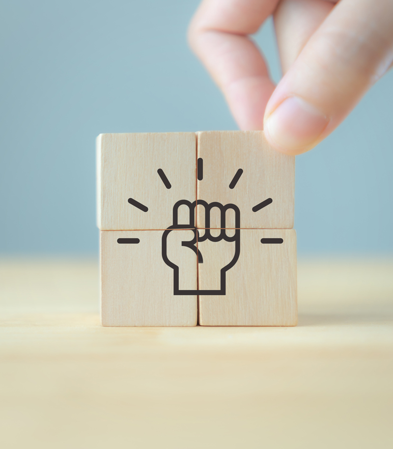 Wooden blocks forming a raised fist, symbolising employee empowerment